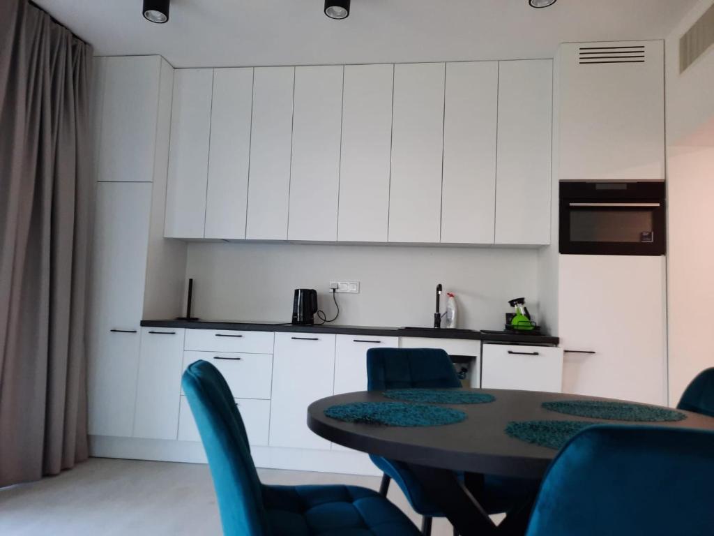 a kitchen with a table and chairs and white cabinets at Apartament Słoneczny Shellter Rogowo in Rogowo