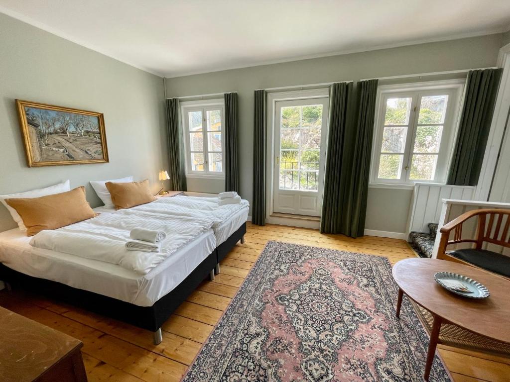 a bedroom with a bed and a table and windows at JANTZENs HOTEL in Gudhjem