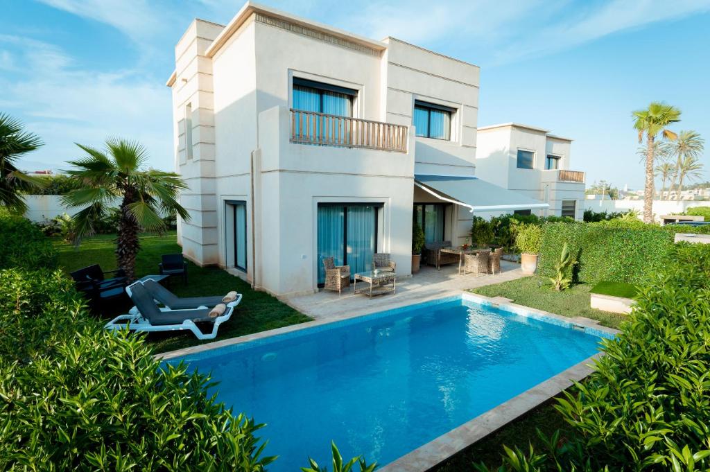 a villa with a swimming pool in front of a house at Villa 10 Palmeraie Golf Agadir in Agadir