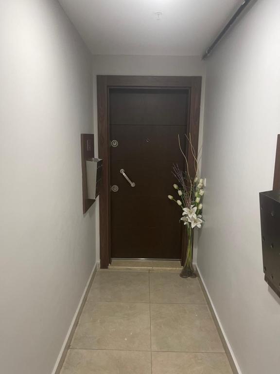 einen Flur mit einer schwarzen Tür und einer Vase voller Blumen in der Unterkunft You are welcome البيت بيتك in Avcılar