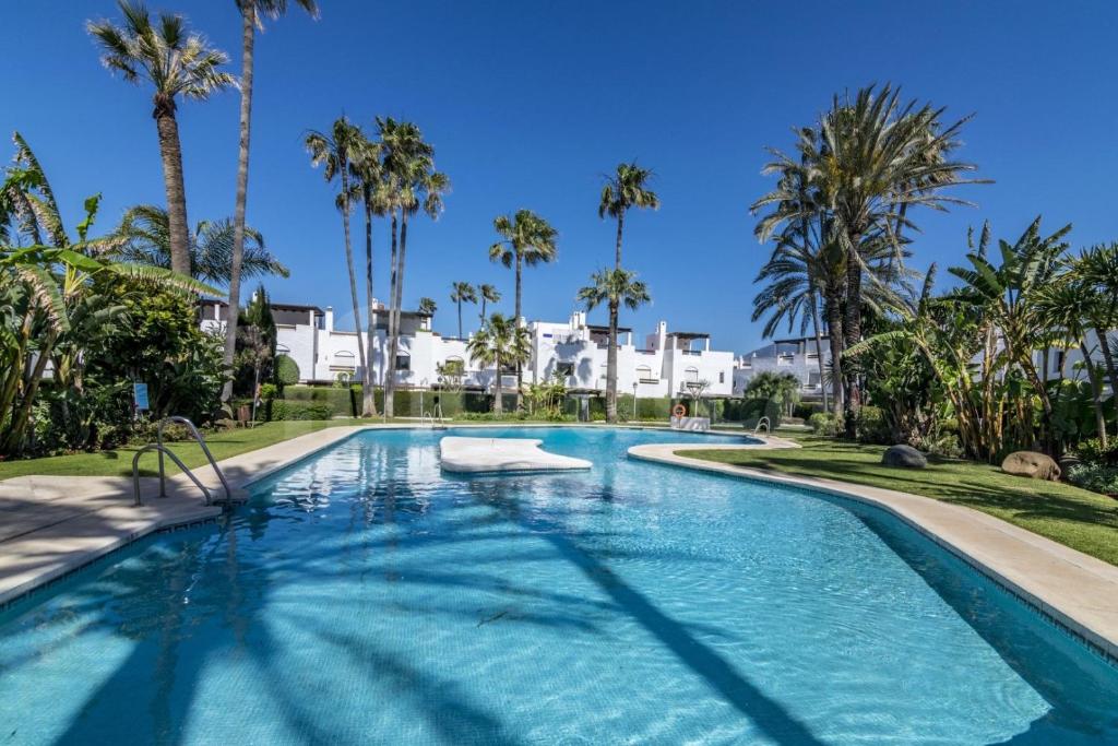 una gran piscina con palmeras en el fondo en Homey Home Guadalvillas 91, en Marbella