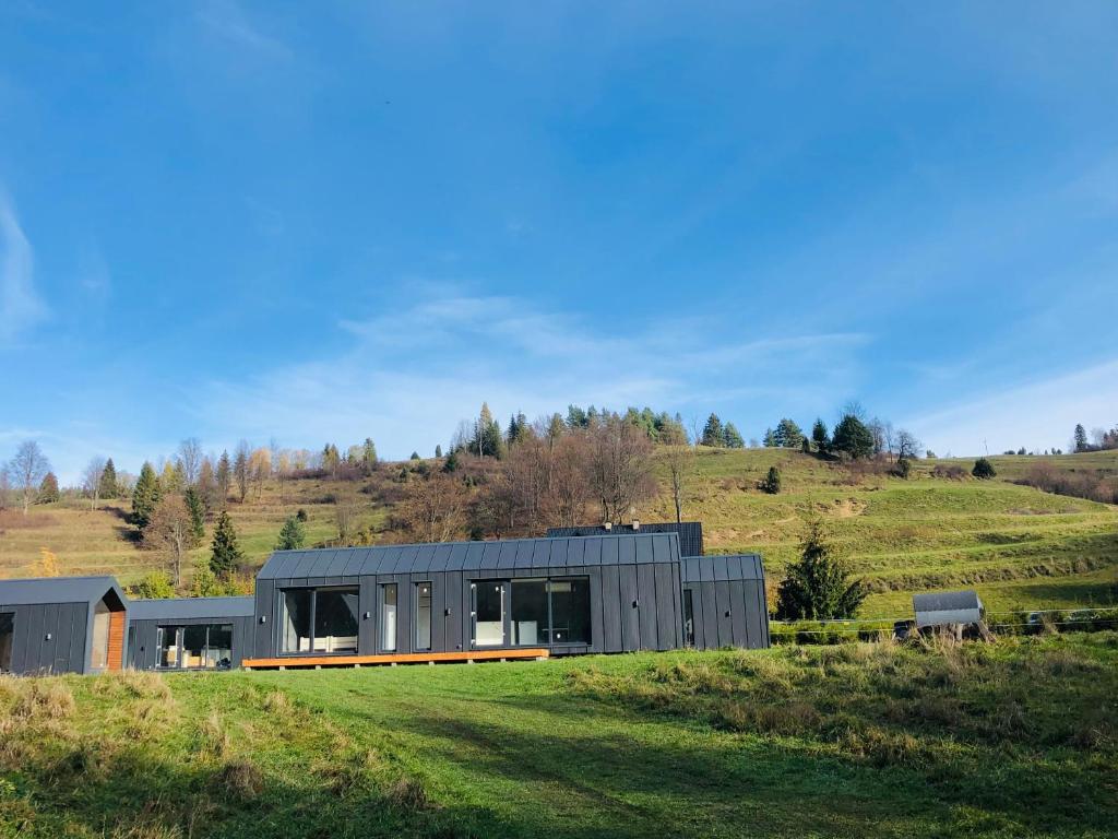 una casa moderna en una colina con un campo verde en Chyża Zagroda, en Jaworki