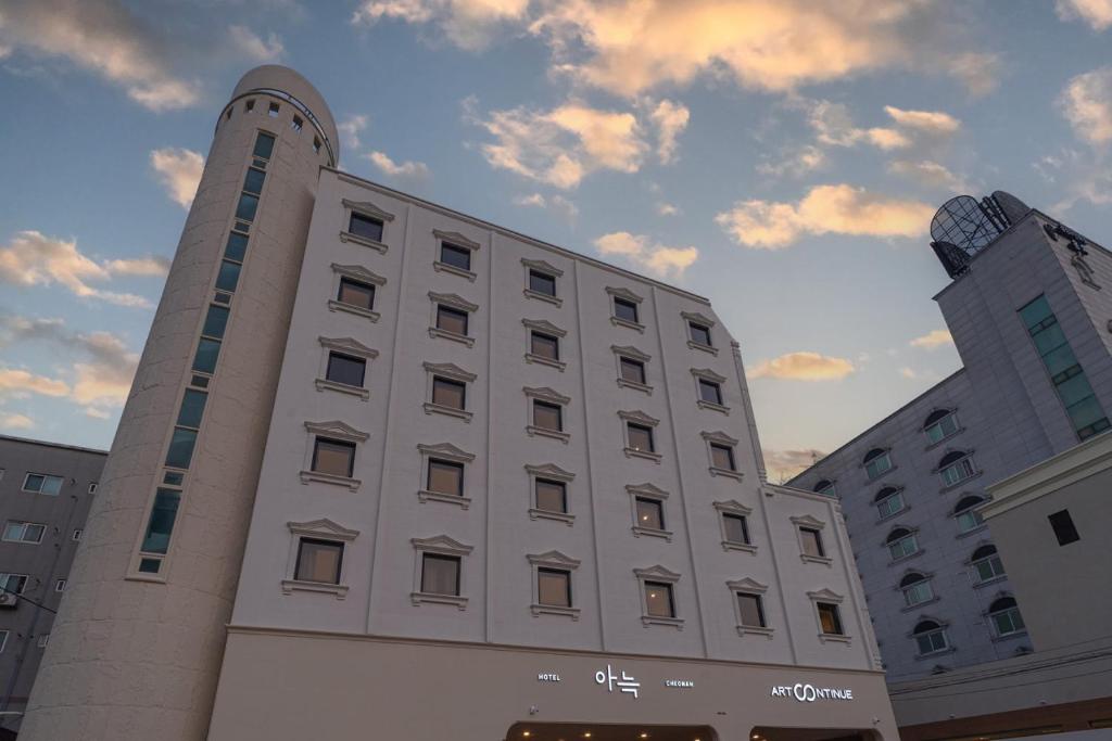 a large white building with a clock tower on it at Aank Hotel Cheonan Station 2 in Cheonan