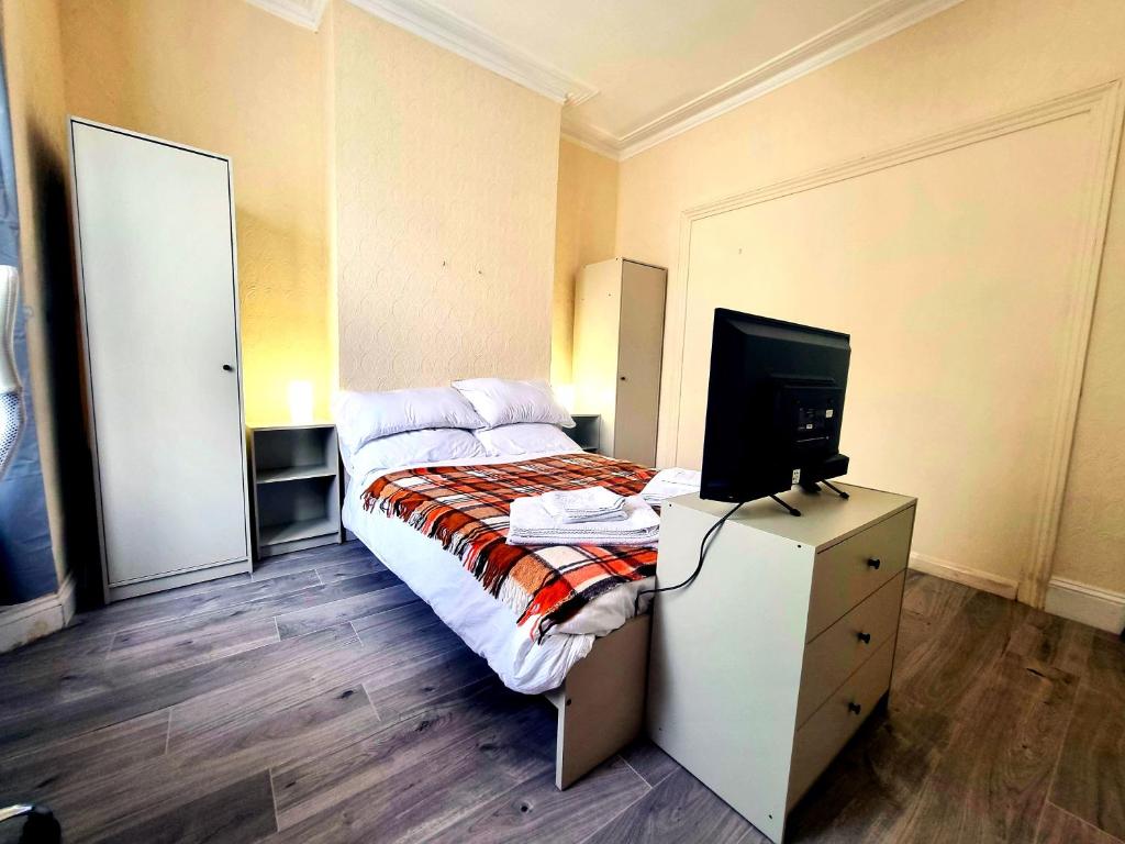 een slaapkamer met een bed en een televisie op een dressoir bij Orford Village Room in Londen