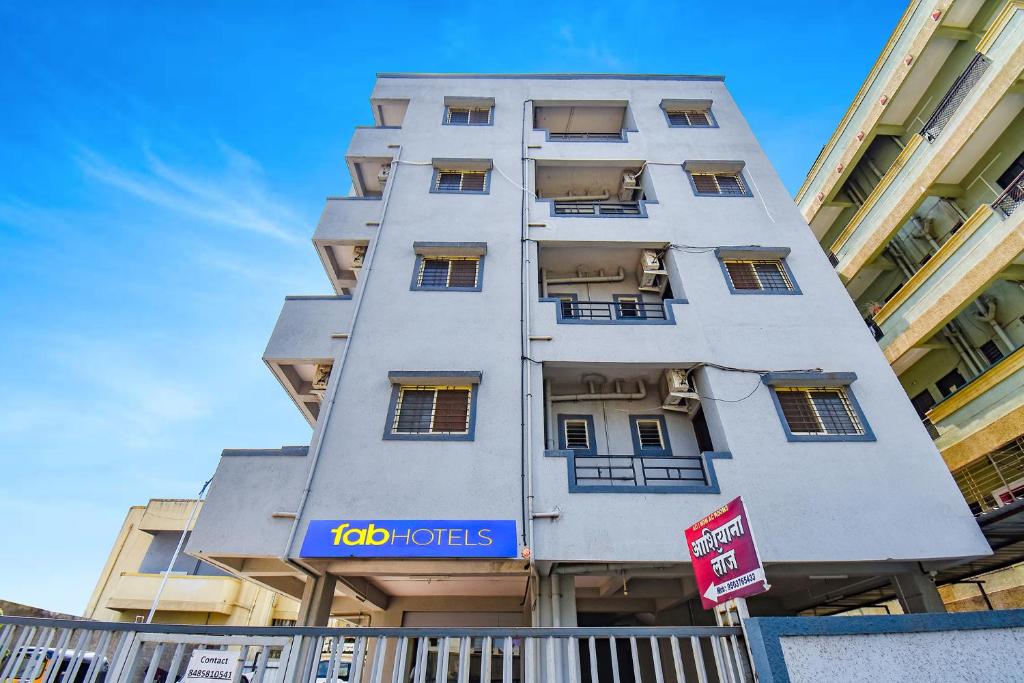 a tall white building with a sign on it at FabHotel Ashiyana Lodge in Pune