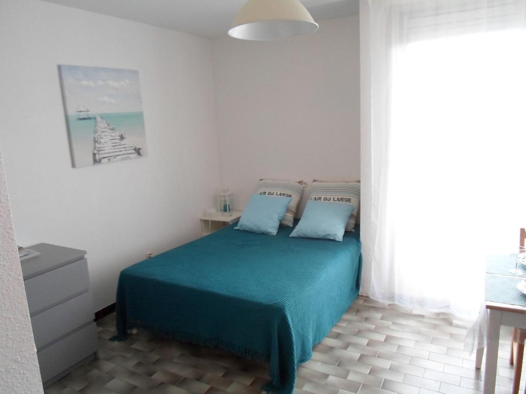- une chambre avec un lit doté de draps bleus et une fenêtre dans l'établissement Studio Balaruc-les-Bains, 1 pièce, 2 personnes - FR-1-503-87, à Balaruc-les-Bains