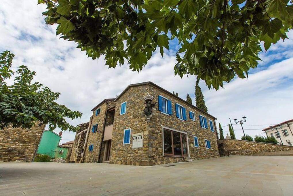 a stone building with blue windows on a street at Santomas apartments in Šmarje
