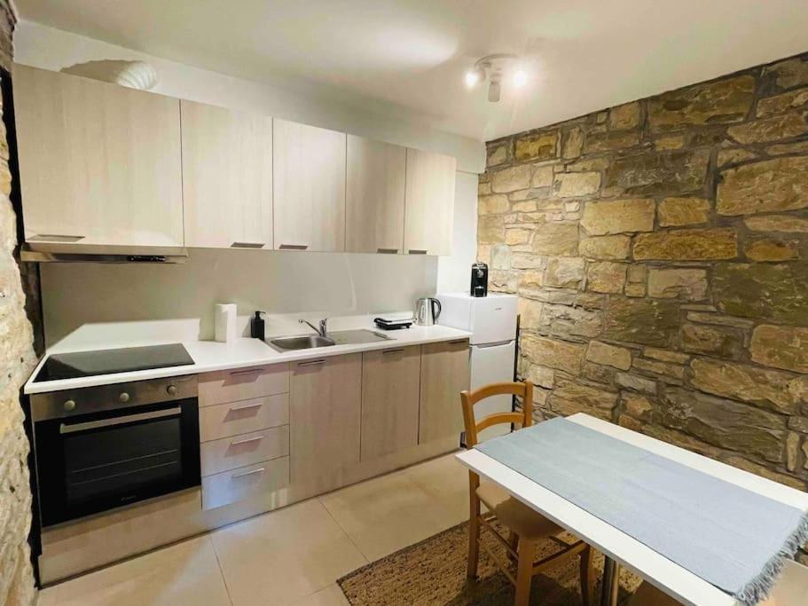 a kitchen with a table and a stone wall at Santomas apartments in Šmarje