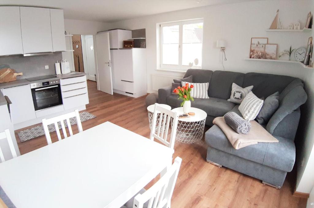 a living room with a gray couch and a kitchen at Wiesenschlössle in Sagard