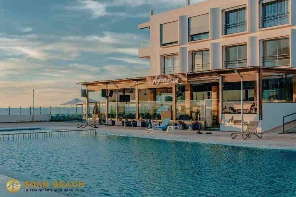 un hôtel avec une piscine en face d'un bâtiment dans l'établissement Appartement pied dans l’eau à 10 min d’Agadir, à Aourir