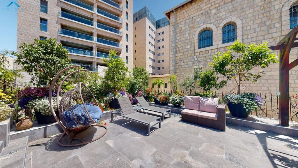een patio met stoelen en een schommel en planten bij VILLA MAMILLA - Boutique suites in Jeruzalem