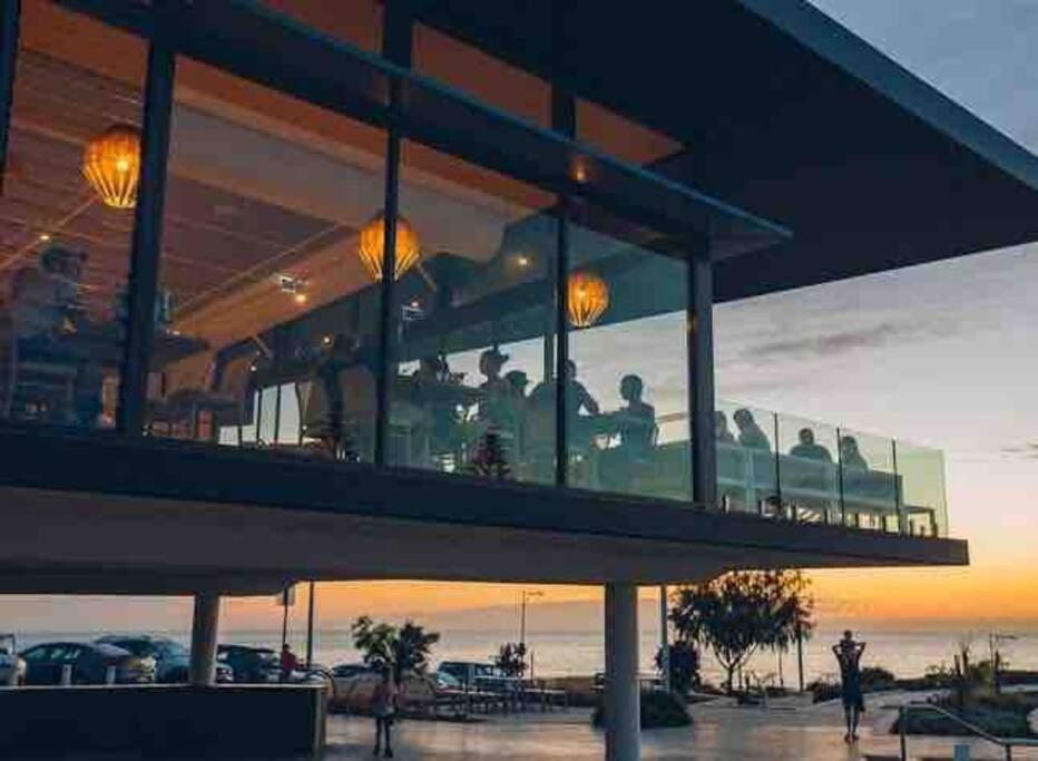 a group of people sitting on a balcony watching the sunset at Apartment close to the beach in Jindalee