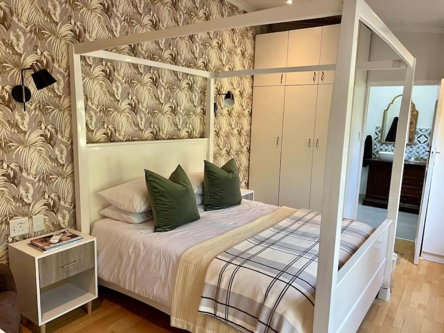 1 dormitorio con cama con dosel y almohadas verdes en Stirling Cottage en Durban