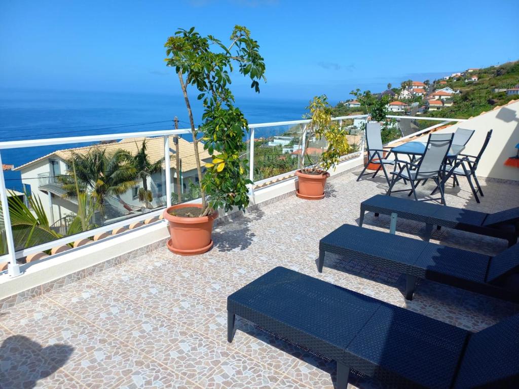 a balcony with blue benches and the view of the ocean at Casa Dos Ramos in Arco da Calheta