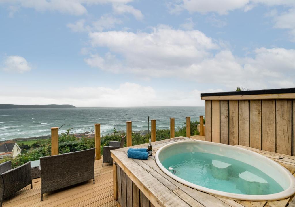 a hot tub on a deck with a view of the ocean at The Albatross 12 in Woolacombe