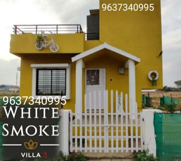 een geel huis met een wit hek ervoor bij WHITE SMOKE villa in Igatpuri