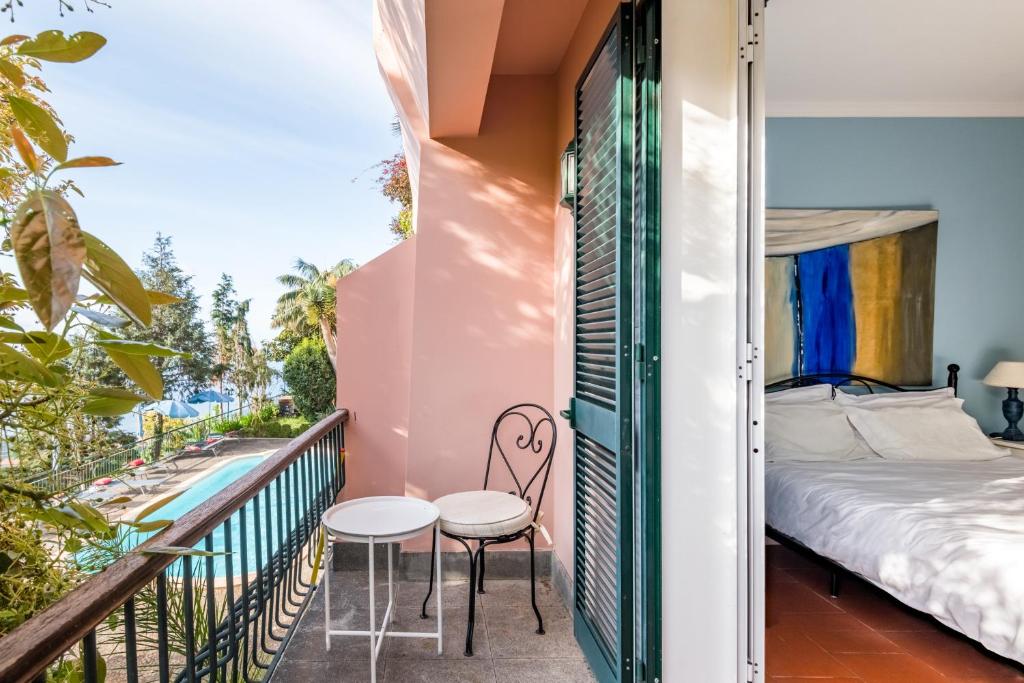een balkon met een bed en 2 stoelen bij Villa Alto Boutique Hotel in Ponta do Sol