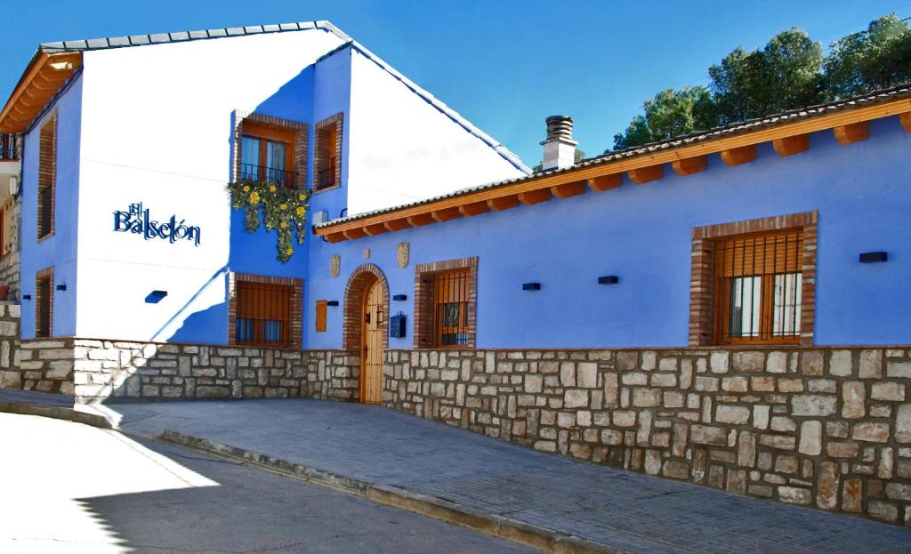 a blue and white house with a stone wall at El Balsetón in Peñalba