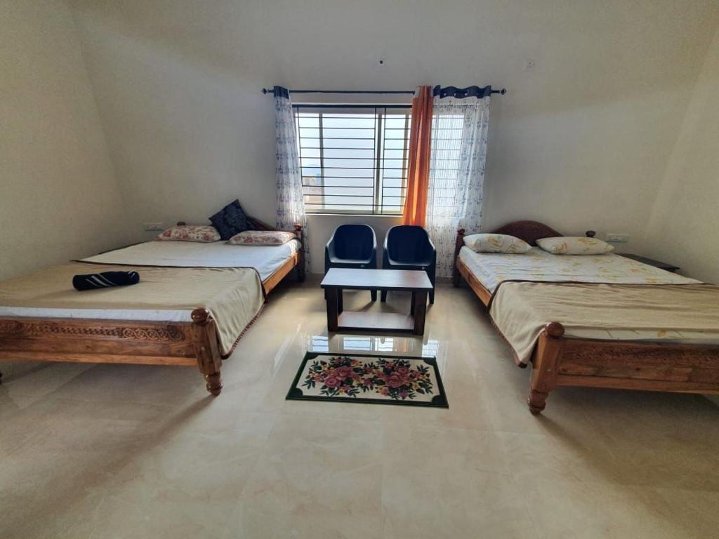 Cette chambre comprend 3 lits, une table et une chaise. dans l'établissement Fourseason frankcottage, à Chikmagalur