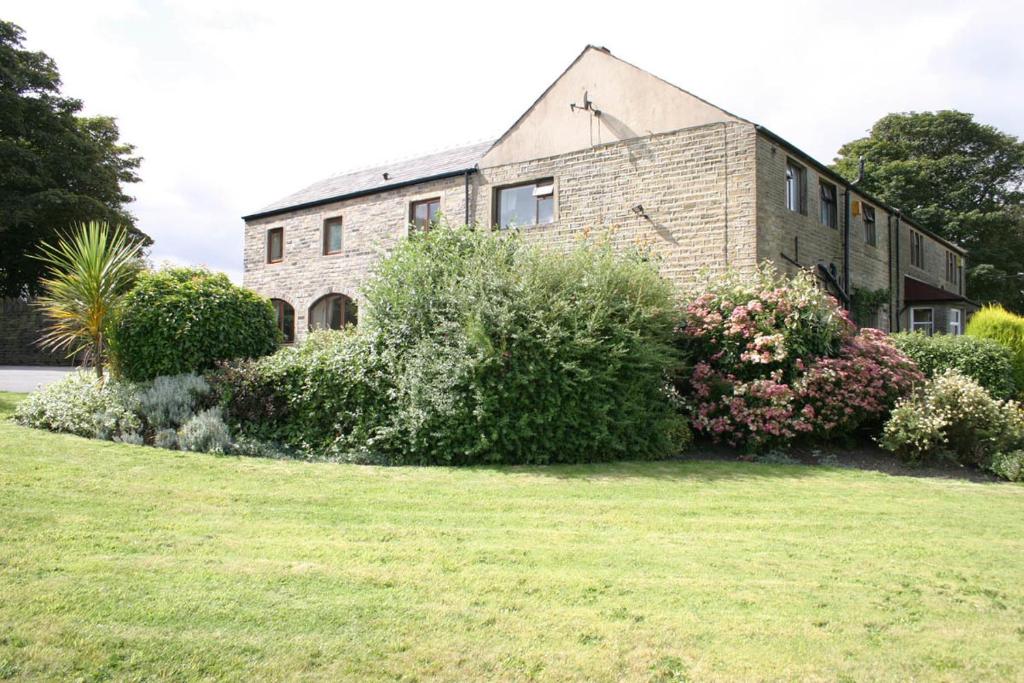 ein Backsteinhaus mit Rasen davor in der Unterkunft Ackroyd House in Holmfirth