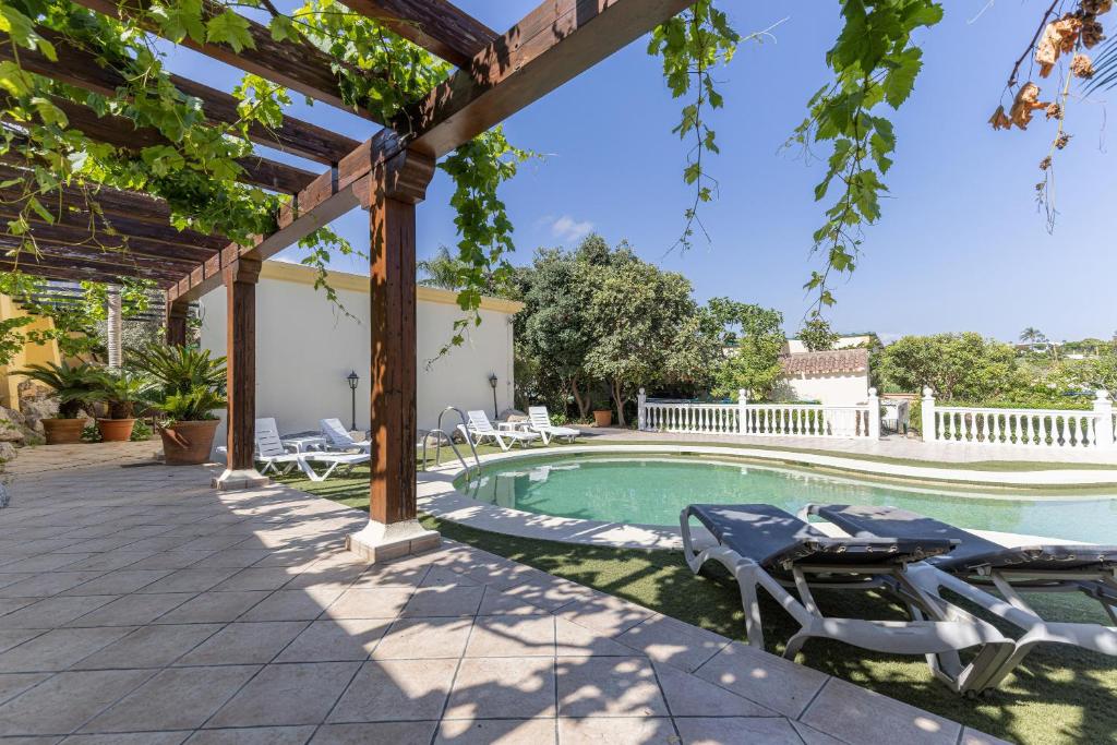 a swimming pool with chairs and a pergola at Estudio Casa Marie in Estepona