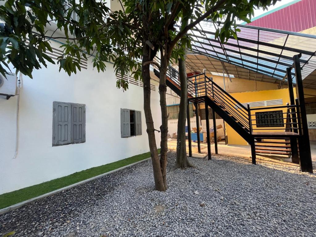 a tree in front of a building with a staircase at Por Chey Hostel in Battambang