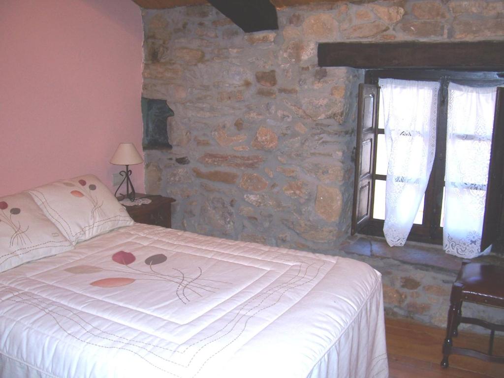 ein Schlafzimmer mit einem Bett und einer Steinmauer in der Unterkunft Las Medulas Los Telares in Las Médulas
