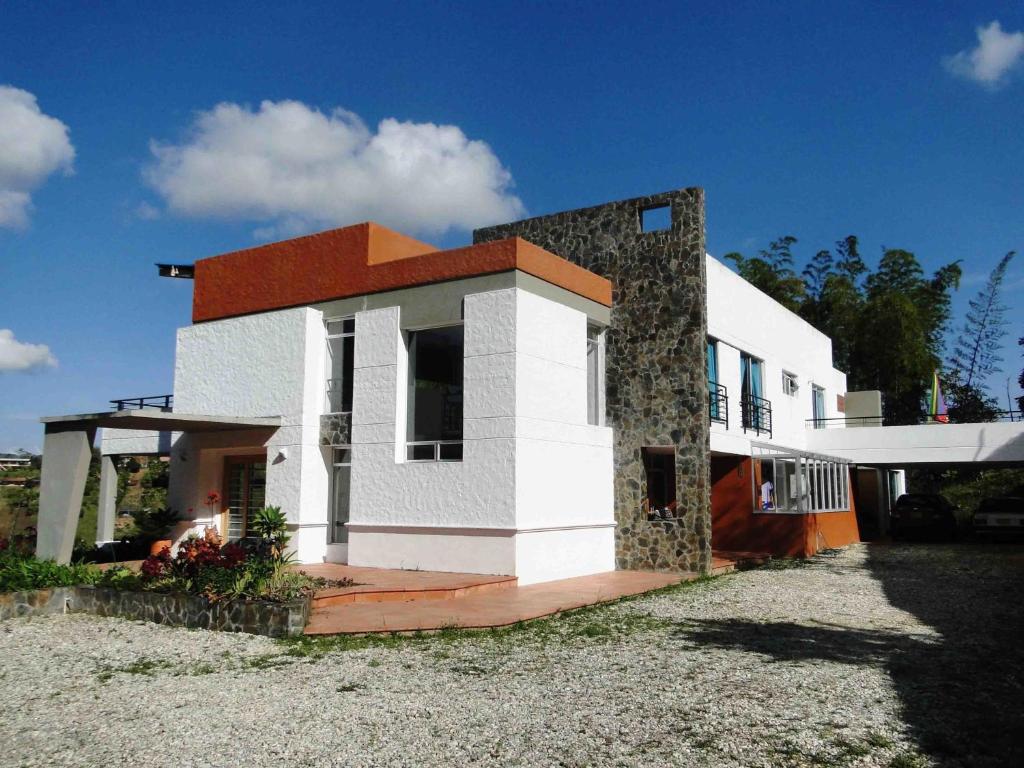 ein weißes und orangefarbenes Haus mit einem Hof in der Unterkunft Hotel Familiar El Remanso Del Agua in Guatapé