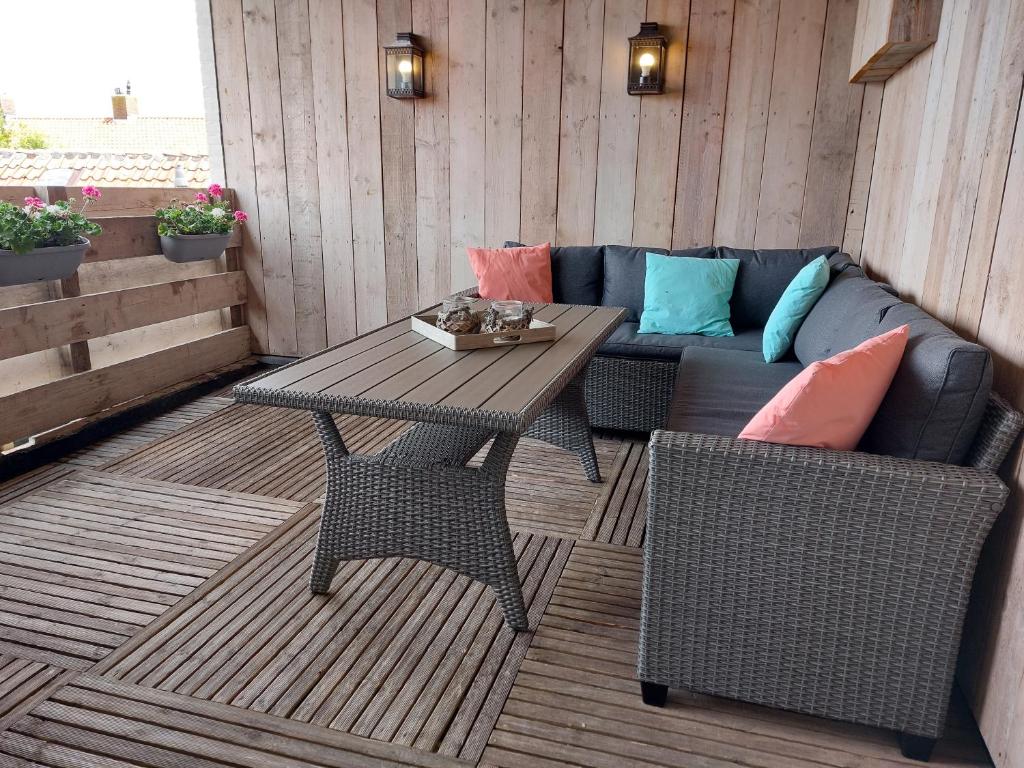 a patio with a bench and a table and a couch at Appartement met inpandig balkon, 150 meter verwijderd van strand en centrum in Zoutelande