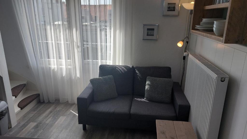 ein Wohnzimmer mit einem Sofa und einem Fenster in der Unterkunft Appartement vlakbij strand en centrum in Zoutelande