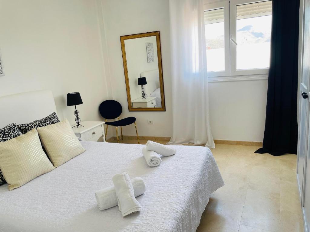 a bedroom with a white bed with towels on it at Apartamentos Dulcemar Frente al Mar con zona SPA in San José
