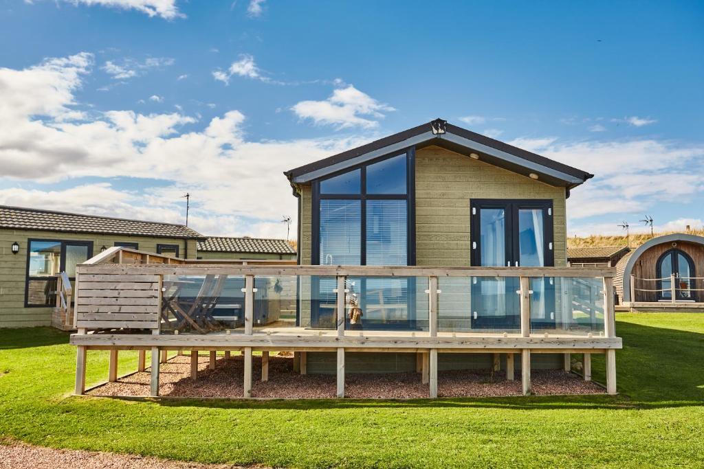a house with a large glass deck in the yard at Sauchope Links Holiday Lodge and Glamping Park in Crail