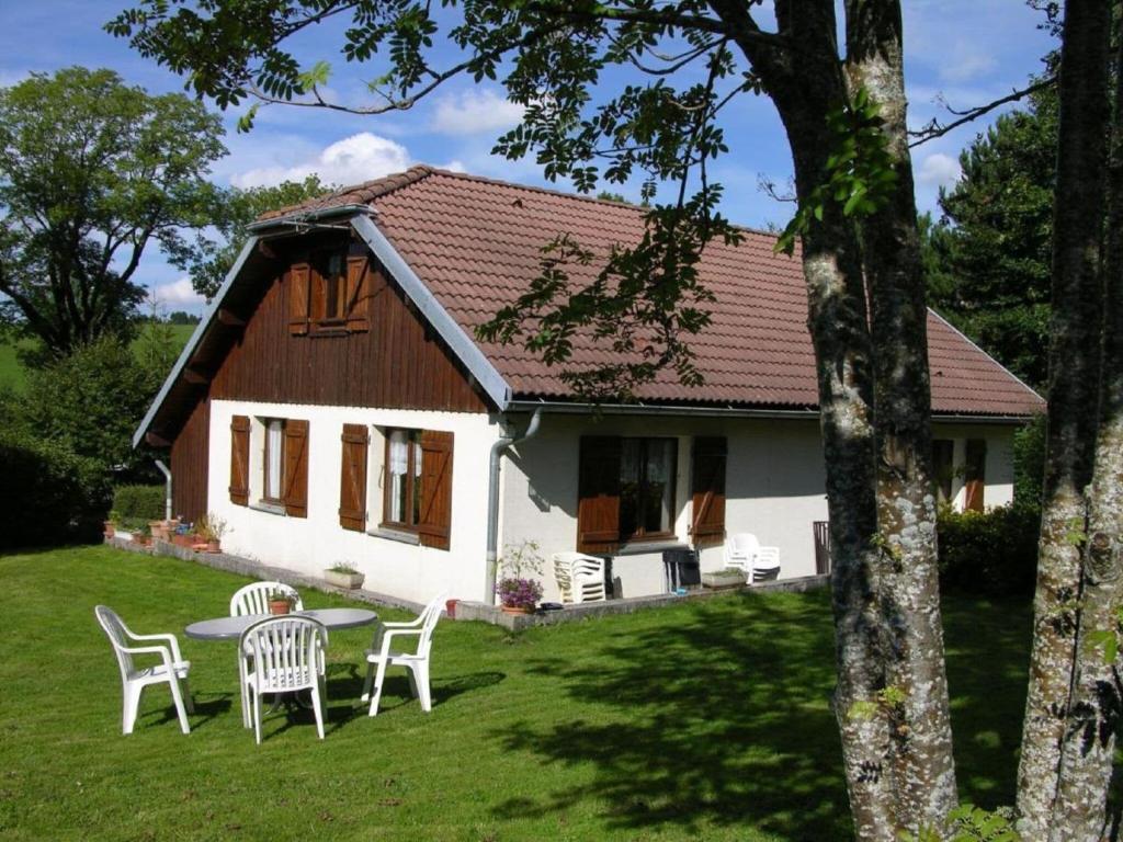 ein weißes Haus mit einem Tisch und Stühlen im Hof in der Unterkunft Gîte de la Marandine in Métabief with garden in Métabief