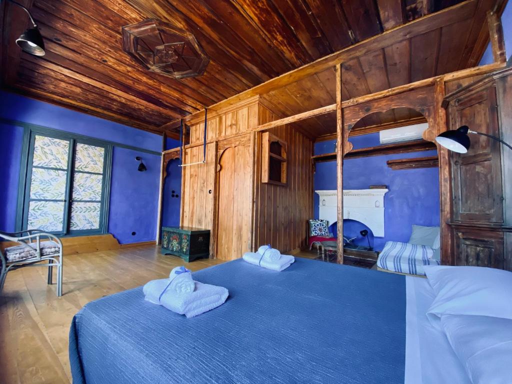 1 dormitorio con 1 cama azul y paredes de madera en Kasa Antika en Meyisti