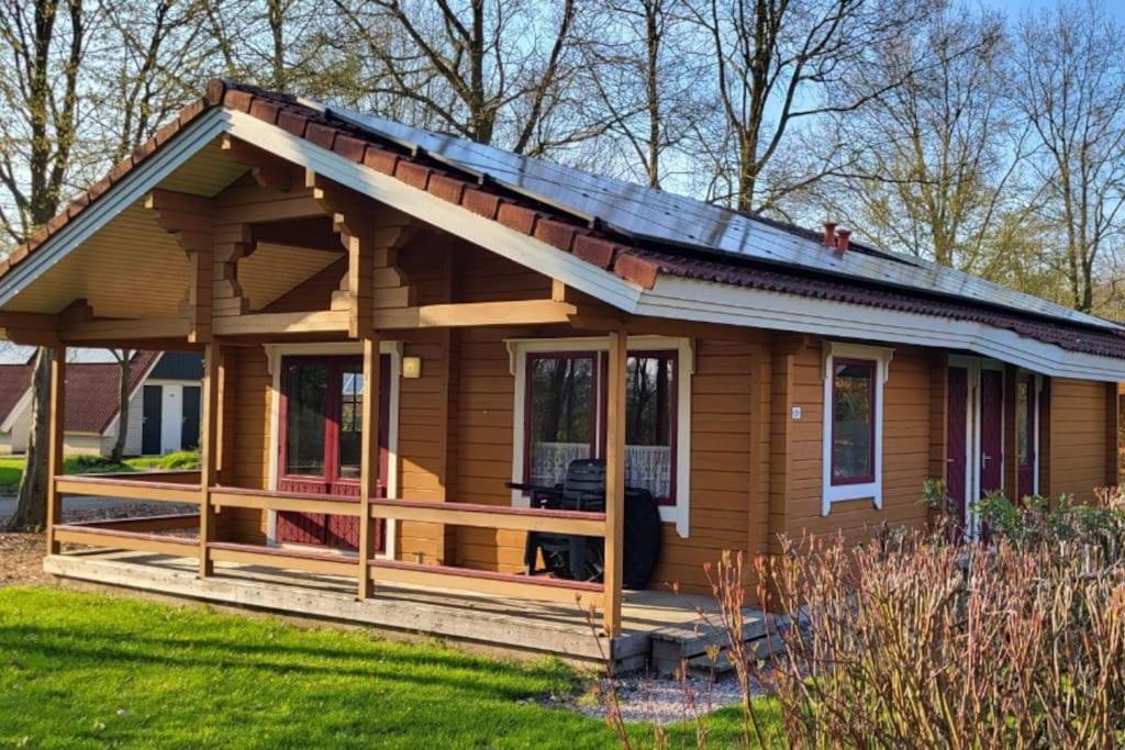 a log cabin with a porch and a deck at Chalet Uppsala, Plus Sauna in Gramsbergen