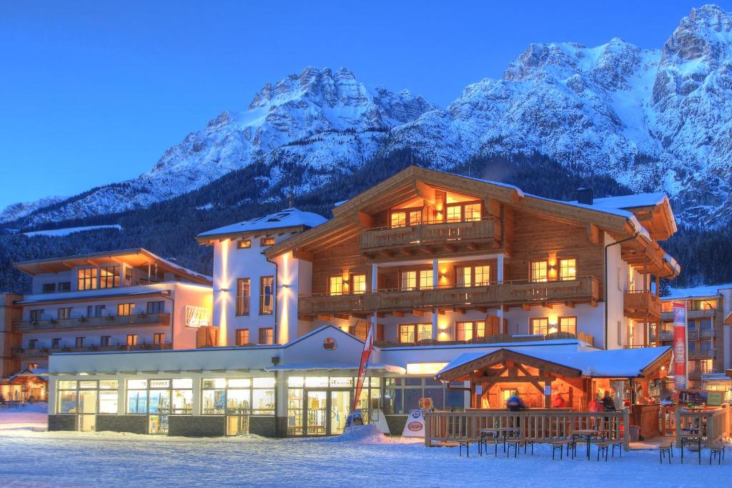 a ski lodge with mountains in the background at Tarlack Appartements Hütten 34 in Leogang