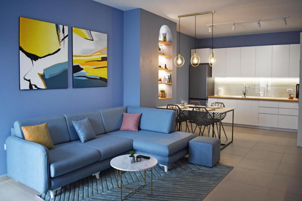 a living room with a blue couch and a kitchen at Vibrant Apartment in Tirana