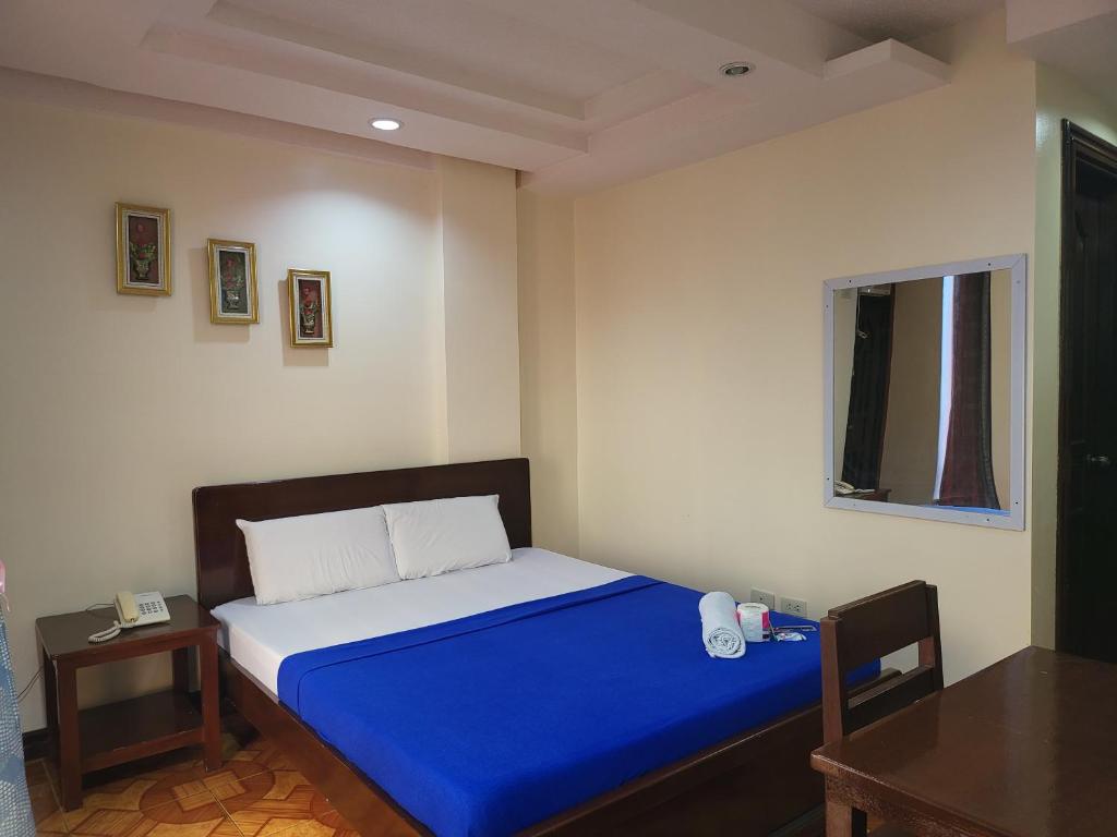 een slaapkamer met een bed met blauwe lakens en een tafel bij Rooms R Us - Voyagers Palace in Puerto Princesa City