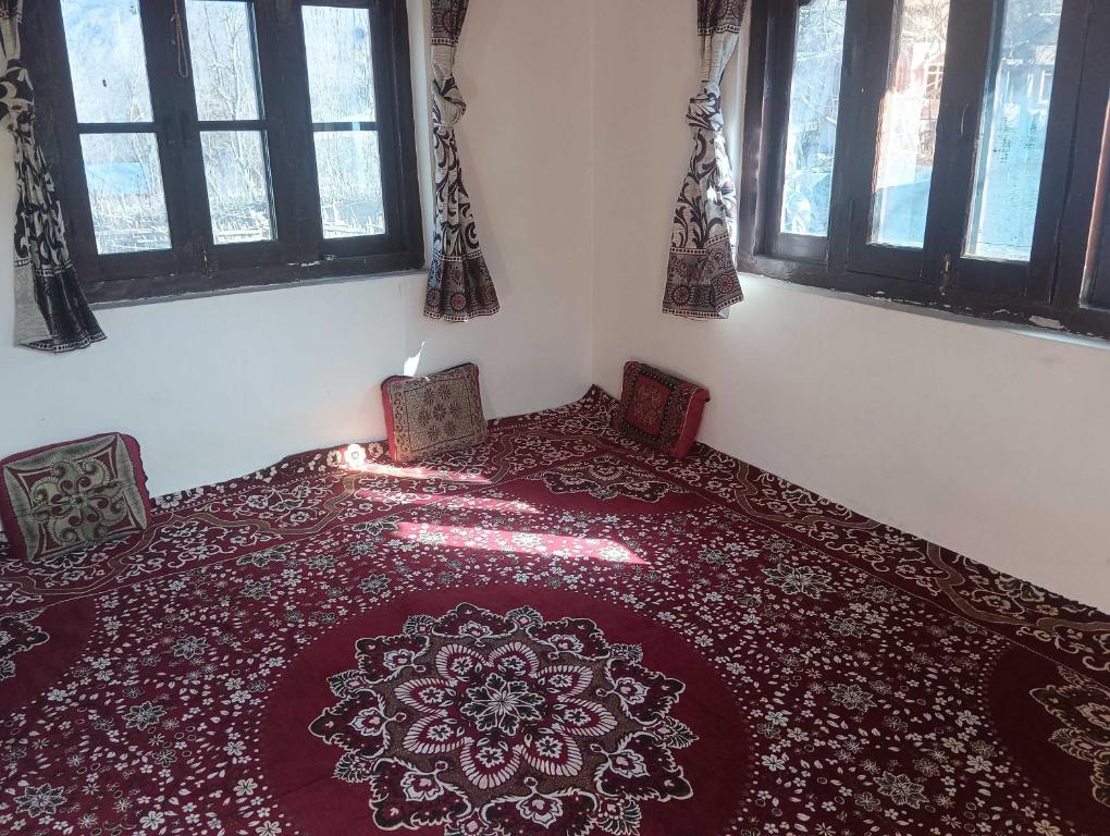 a room with a bed with a red carpet and windows at OYO Home Fatima's Homestay in Wāngom