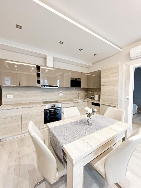 kuchnia z drewnianym stołem i białymi krzesłami w obiekcie MyFlat Viewpoint 57 w Siófoku