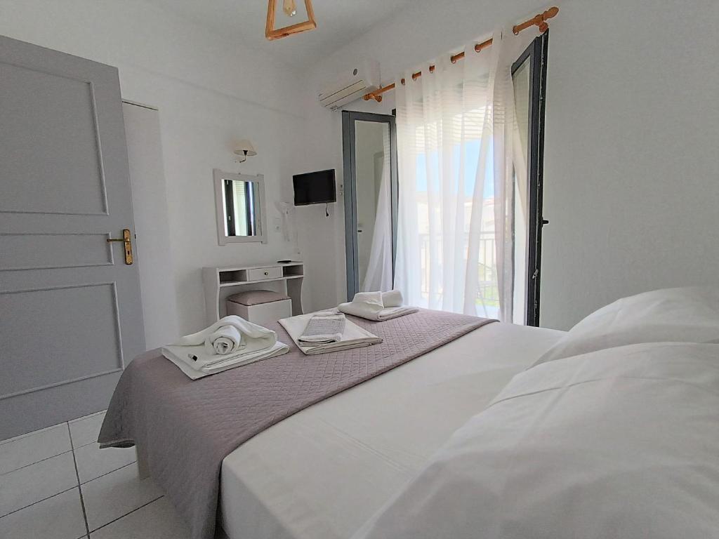 a white bedroom with a bed with towels on it at Emilia Apartments in Elounda