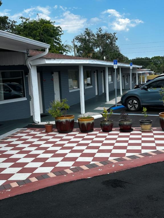 a house with a checkered parking lot with potted plants at Red Carpet Inn Daytona Beach in Daytona Beach