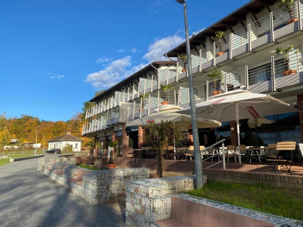 un bâtiment avec des tables et des parasols devant lui dans l'établissement Pensjonat Długie, à Długie