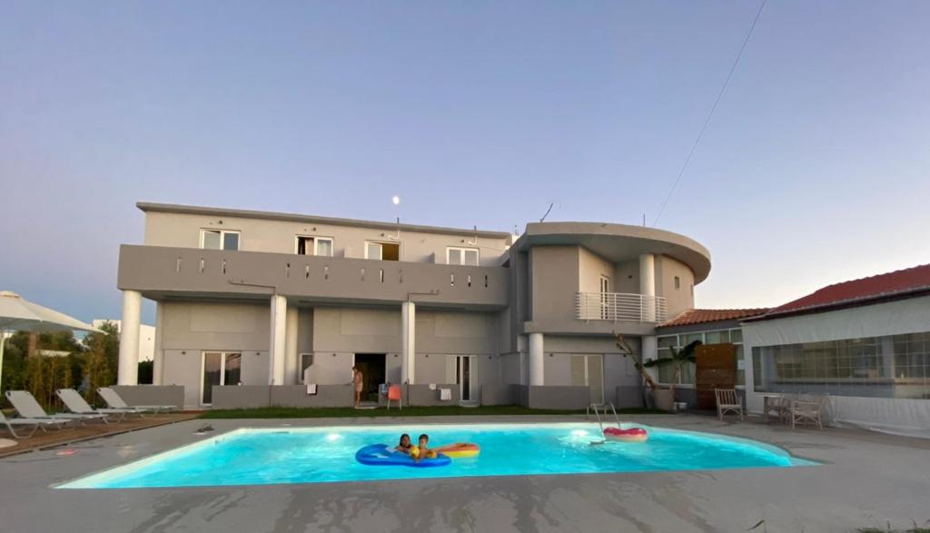 dos personas en una piscina frente a una casa en Banana Moon, en Adelianos Kampos
