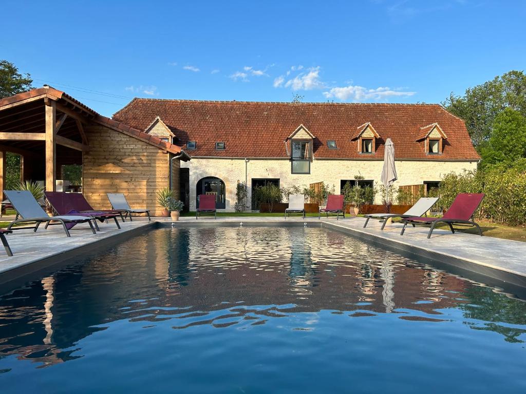 a pool in front of a house with chairs next to it at Les Noyers De Gaudelle in Saint-Sozy