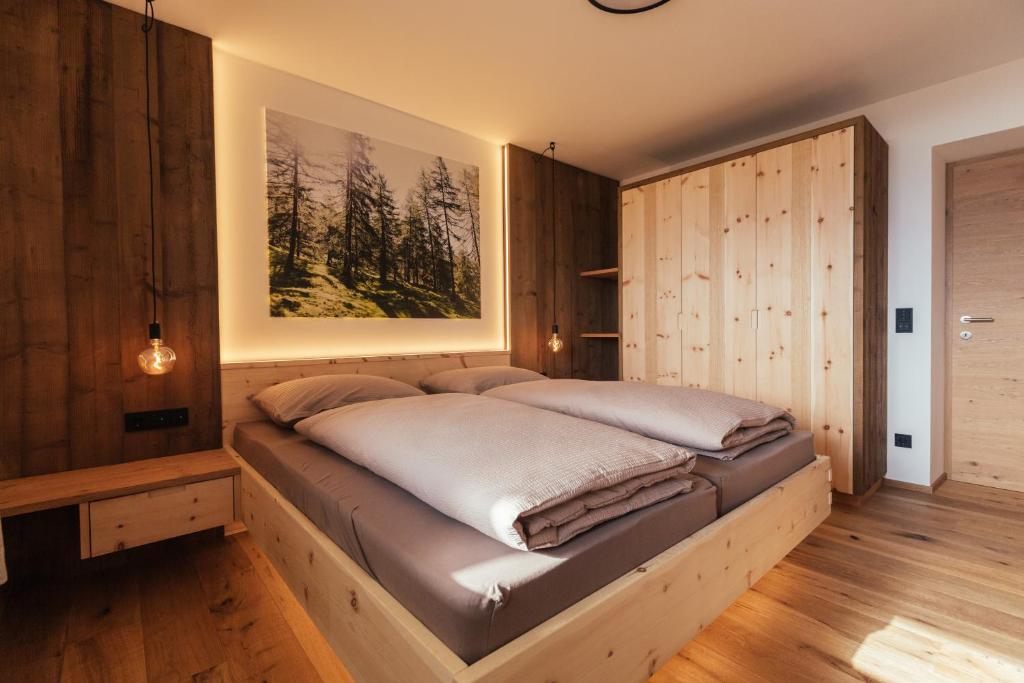 Bett in einem Zimmer mit einer Holzwand in der Unterkunft Alpenglow Apartments in Klobenstein