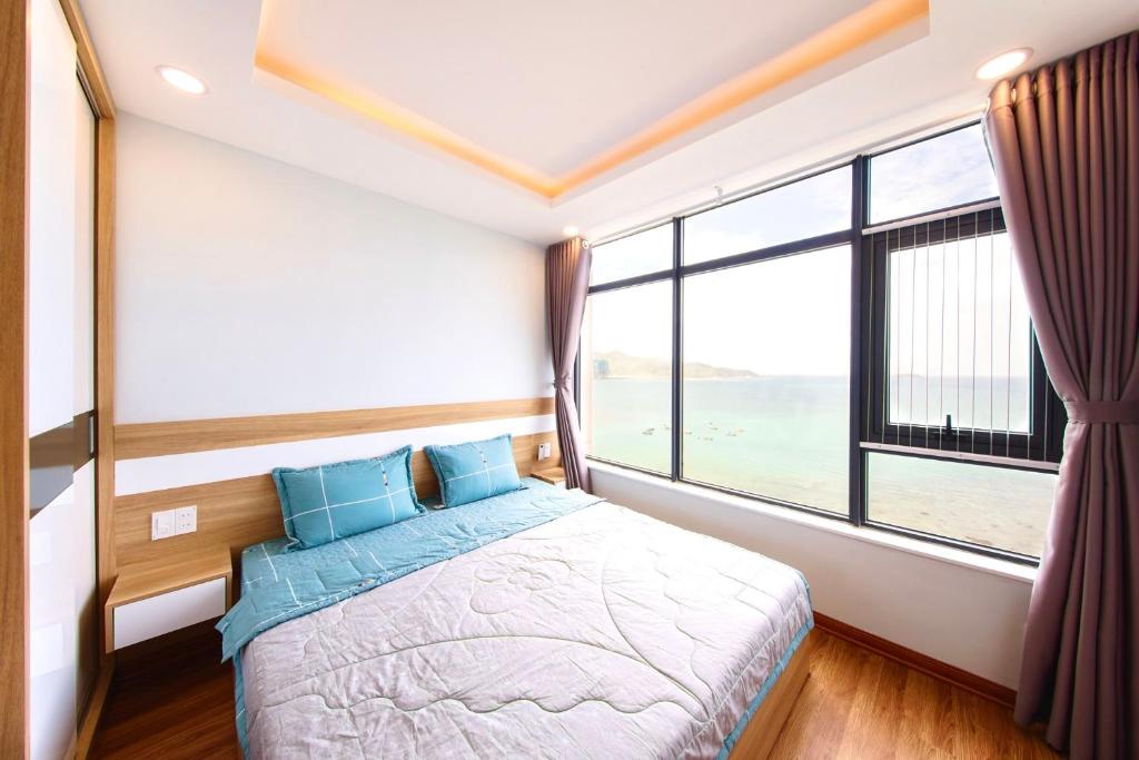 a bedroom with a bed and a large window at Căn Hộ Du Lịch Biển Nha Trang in Nha Trang