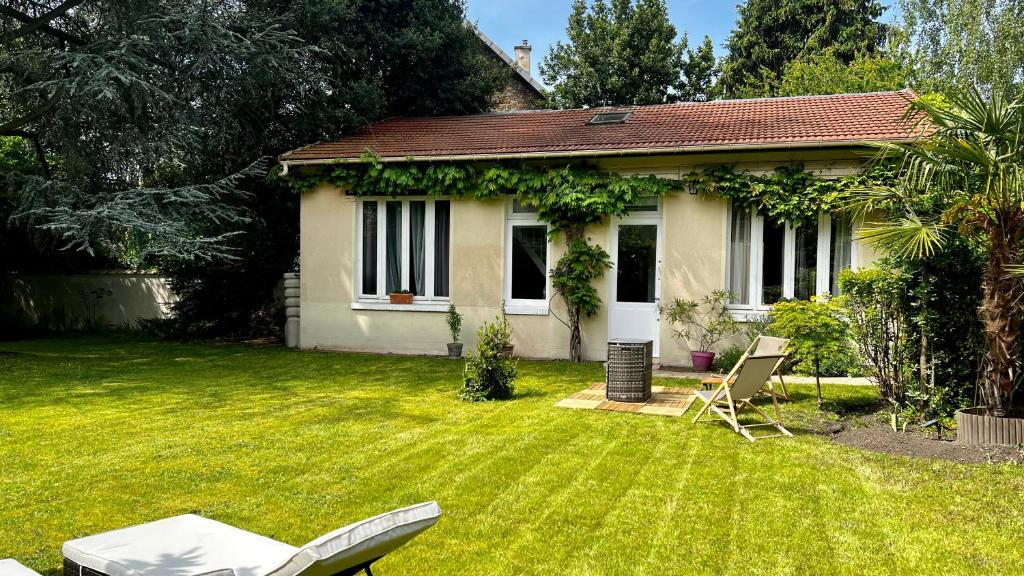 una pequeña casa blanca con un patio con una silla en L Annexe - Parenthèse Champêtre PARIS DISNEYLAND en Gagny