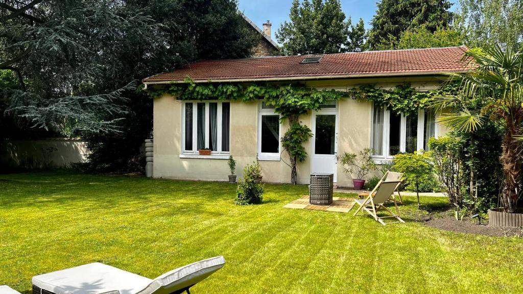 a small white house with a yard with a chair at L Annexe - Parenthèse Champêtre PARIS DISNEYLAND in Gagny