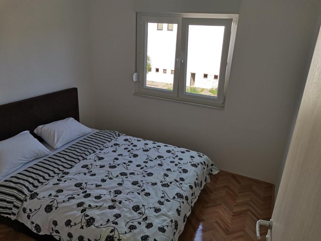 a bed with a black and white comforter and a window at AD Apartman Bileća in Bileća